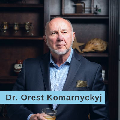 Dr. Orest Komarnyckyj in a suit holding a cocktail
