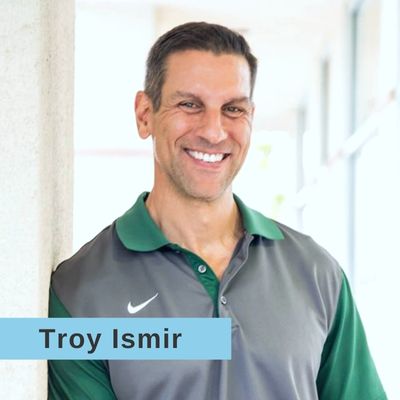 Smiling headshot of Troy Ismir wearing a green and gray polo shirt
